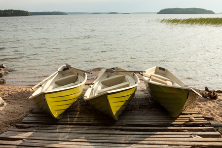Lake with a wooden pier and a three boats in Finland.の写真素材