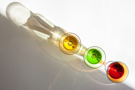 Multicolored glasses on a white background; interesting shadows and the place for the text.の写真素材