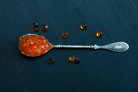 Red caviar in the old silver spoon on a dark background.の写真素材
