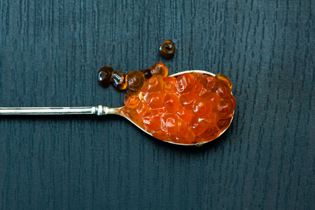 Red caviar in the old silver spoon on a dark background.の写真素材