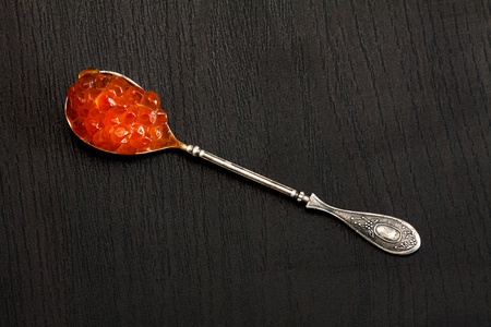 Red caviar in the old silver spoon on a dark background.の写真素材