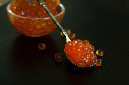 Red caviar in the old silver spoon on a dark background.の写真素材
