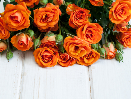 Bouquet of beautiful orange roses on white wooden table.の写真素材