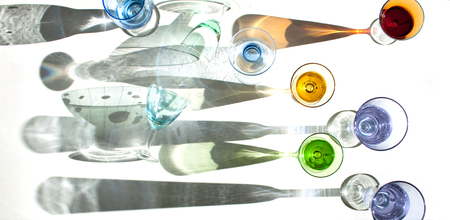 Multicolored glasses on a white background and interesting shadows.の写真素材