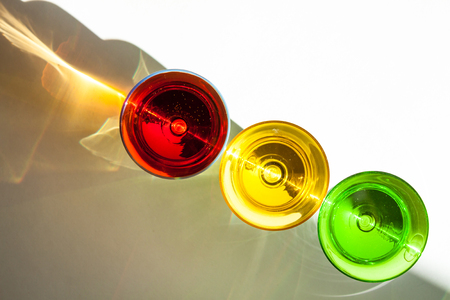 Multicolored glasses on a white background; interesting shadows and the place for the text. Diagonal traffic light.の写真素材