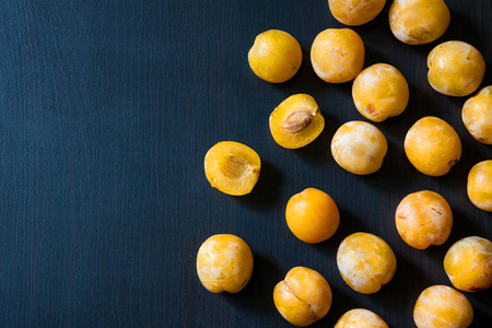Yellow plums on a dark blue wood background.