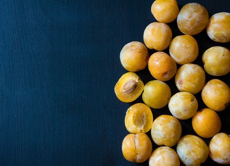 Yellow plums on a dark blue wood background.の写真素材