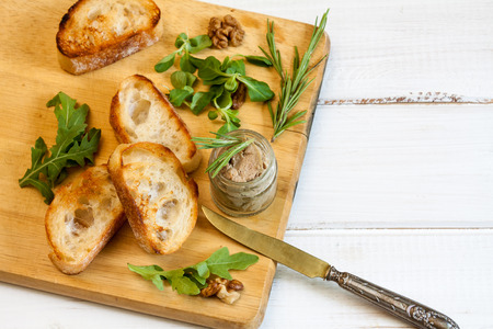 Toasty bread, jar with paste, herbs and wallnuts on a wooden board.の写真素材