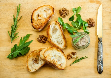 Toasty bread, jar with paste, herbs and wallnuts on a wooden board.の写真素材
