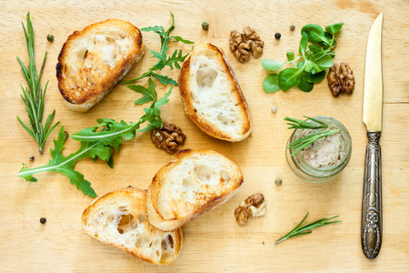 Toasty bread, jar with paste, herbs and wallnuts on a wooden board.の写真素材