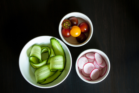 Bowls with ingredients for salad on a dark background.の写真素材