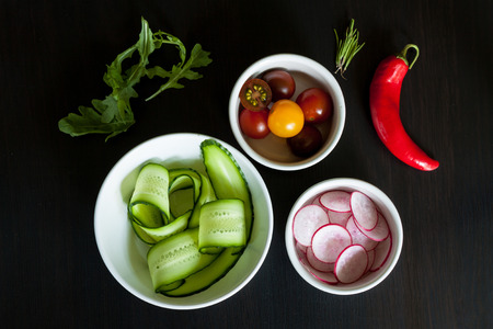 Bowls with ingredients for salad on a dark background.の写真素材