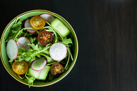 Bowl with salad on a dark background. Space for text.の写真素材