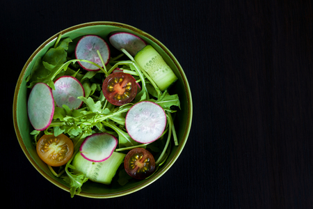 Bowl with ingredients for salad on a dark background. Space for text.の写真素材