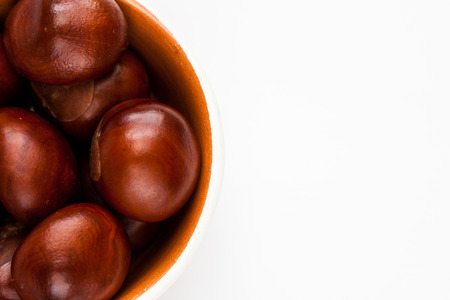 Bowl with autumn chestnuts on a white background.の写真素材