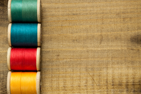 Old wooden coils of thread on a rustic wooden background.