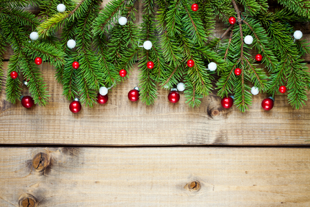 Wide Christmas border composed of fresh fir branches and ornaments in red and white on woodの写真素材