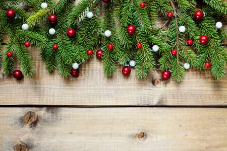 Wide Christmas border composed of fresh fir branches and ornaments in red and white on woodの写真素材