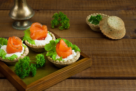 Tartlets with salmon, cream cheese and salad on rustic woodの写真素材