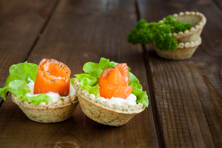 Tartlets with salmon, cream cheese and salad on rustic woodの写真素材