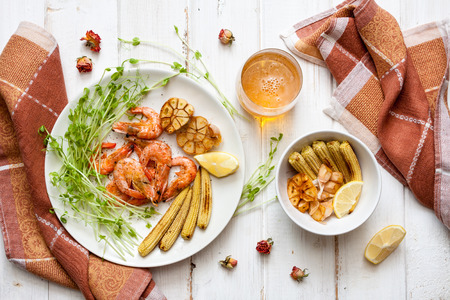 Toasty shrimps, corn and garlic with herbs in the plate on wood table.の写真素材