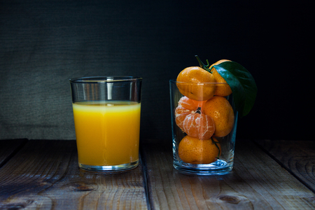 Tangerines (mandarins, citrus fruits) with leaves and juice on rustic woodenの写真素材