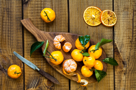 Tangerines (mandarins, citrus fruits) with leaves on rustic woodenの写真素材