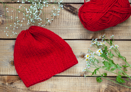 Red knitting wool, knitting needles and flowers on woodenの写真素材