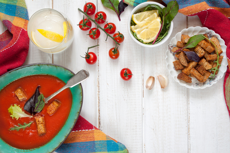 Bowl with gaspacho (tomatoes soup) and ingredients on rustic white table.の写真素材