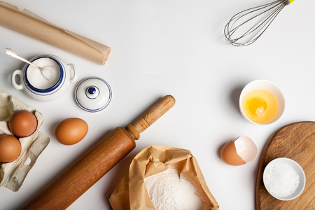 Top view with kitchen tools and ingredients for cake or cookies: flour, egg, sugar on whiteの写真素材