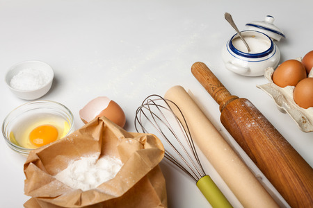 Top view with kitchen tools and ingredients for cake or cookies: flour, egg, sugar on whiteの写真素材