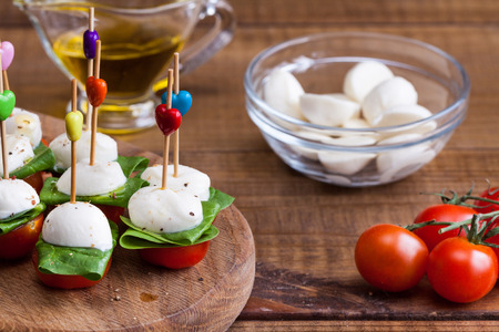 Refreshment with cherry tomatoes, mozzarella and spinach on a wooden board.の写真素材