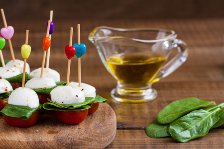Refreshment with cherry tomatoes, mozzarella and spinach on a wooden board.の写真素材