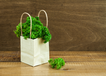 Parsley bunch in a paper ecologic package on a wooden background.の写真素材