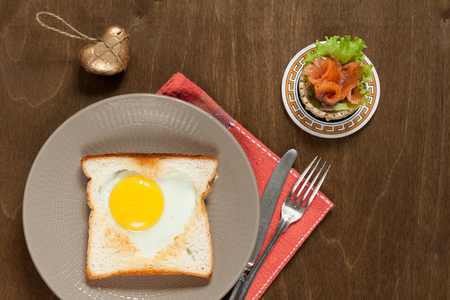 Breakfast with heart fried eggs and salmon tartlet.の写真素材