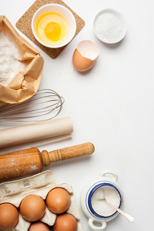 Top view with kitchen tools and ingredients for cake or cookies: flour, egg, sugar on white background. Copy space.の写真素材
