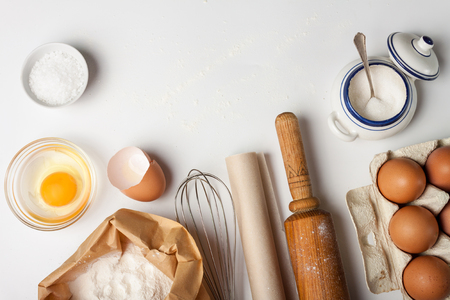 Top view with kitchen tools and ingredients for cake or cookies: flour, egg, sugar on white background. Copy space.の写真素材