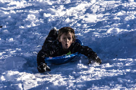 Young Boy Sledding On a Sunny Winter Dayの写真素材