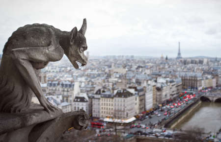demon-faced gargoyle at Cathedral in the foreground, with the whole city of Paris in the background, including the Eiffel Tower.の写真素材