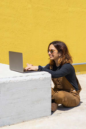 Woman with red headphones sitting on stairs on the street on a sunny day looking at the phone.の写真素材