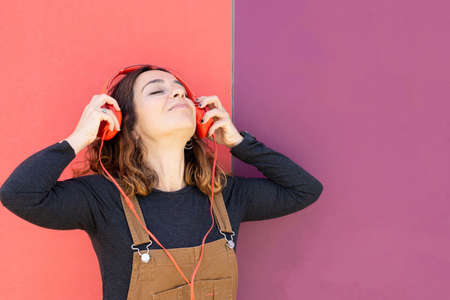Woman with red headphones sitting on stairs on the street on a sunny day looking at the phone.の写真素材