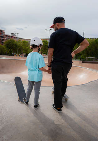 Girl holding her father's hand before learning to skate at a skate parkの写真素材