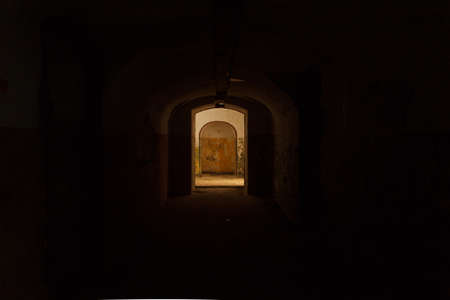 Lighted door at the exit of a dark underground tunnel.