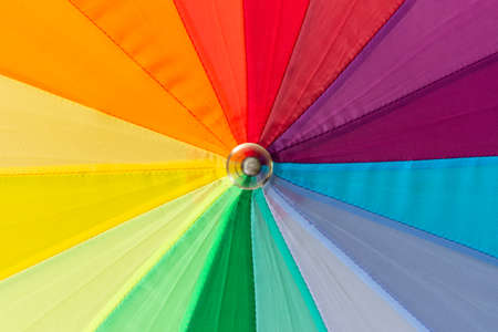 A multicolored rainbow umbrella, photographed close-up.
