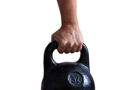 Male hand holding black cast iron sports kettlebell isolated.の写真素材