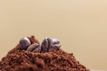 Roasted grains of arabica coffee on ground coffee close-up on a brown background.の写真素材