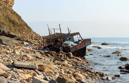 Wooden fishing boat from North Korea, shipwrecked after a storm off the coast of the Russian island,...