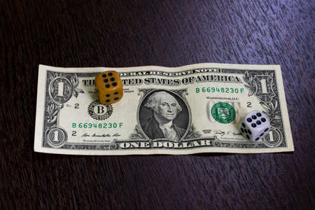 One dollar banknote and two dice lying on the table.