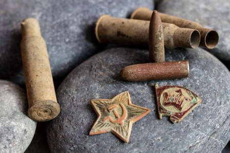 St. Petersburg, Russia - October, 02, 2020: A red star from a military cap and a Komsomol badge, along with casings and bullets from a 7.62mm Mosin rifle, are artifacts of the Soviet Union.のeditorial素材