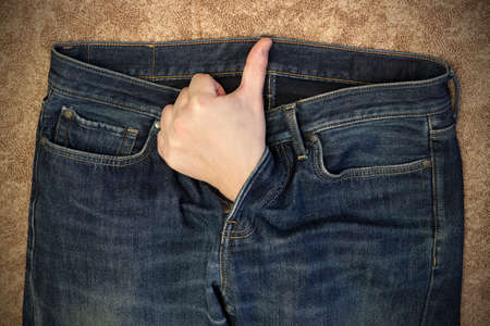 A man's hand, with his thumb raised, protrudes from the fly of his jeans. Treatment of erectile...
